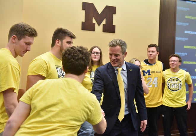 Michigan head basketball coach Dusty May, right, shakes hands with Maize Rage member Emily Vandenbossche, left, of Marine City, before posing for a photo with the group after the press conference at the University of Michigan in Ann Arbor, Mich. on Mar. 26, 2024.
