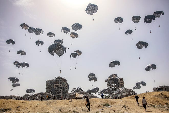 People rush to landing humanitarian aid packages dropped over the northern Gaza Strip on April 23, 2024 amid the ongoing conflict in the Palestinian territory between Israel and the militant group Hamas.