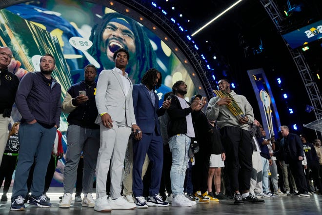 Michigan football players stand on stage before the start of the the second round of the NFL Draft on Friday in Detroit.