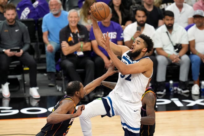 Minnesota Timberwolves center Karl-Anthony Towns, right, drives to the basket against the Kevin Durant, left, during the first half of Game 4 of the NBA basketball first-round playoff series, Sunday, April 28, 2024, in Phoenix.