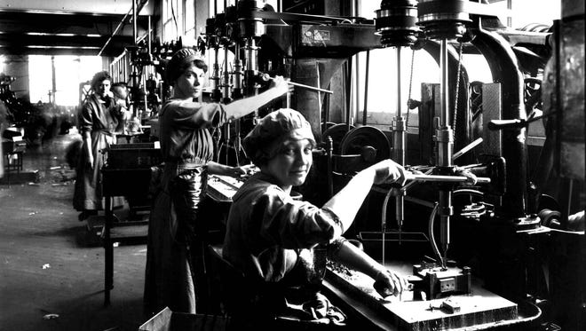 Workers operate drill presses in a munitions shop during the First World War.