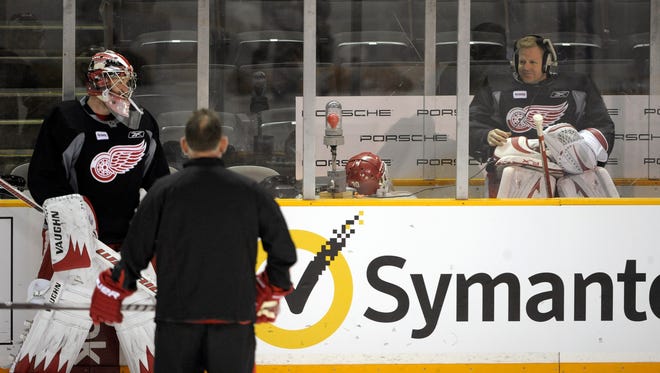Goalie Chris Osgood goofs off inside the penalty box as teammate Jimmy Howard and goaltending coach Jim Bedard watch during practice at HP Pavilion in San Jose, California, April 28, 2011.