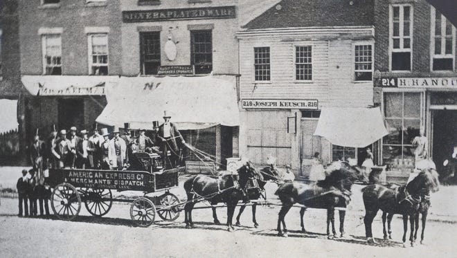 Men in top hats ride in the American Express Co. Merchants' Dispatch wagon along Jefferson Avenue in the 1860s. The street was named in honor of President Thomas Jefferson.  Today it remains Detroit's east-west backbone, following the Detroit River for nearly 64 miles, from 23 Mile in the northeast suburbs to Dixie Highway near Estral Beach, southwest of the city.