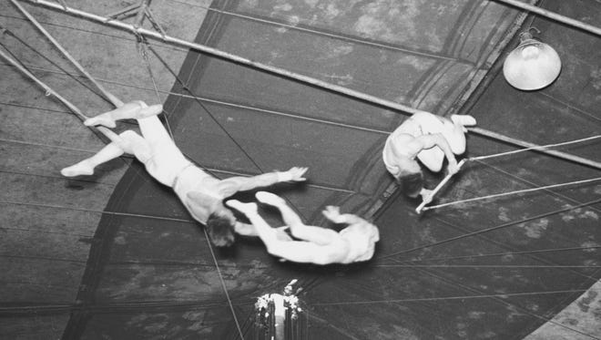 Aerialists fly on their trapeze in a 1936 Detroit performance.