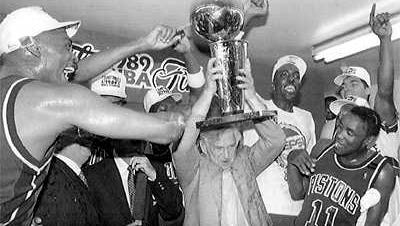 Pistons owner Bill Davidson holds the NBA Championship trophy as the team celebrates a four-game sweep of the Los Angeles Lakers in 1989.