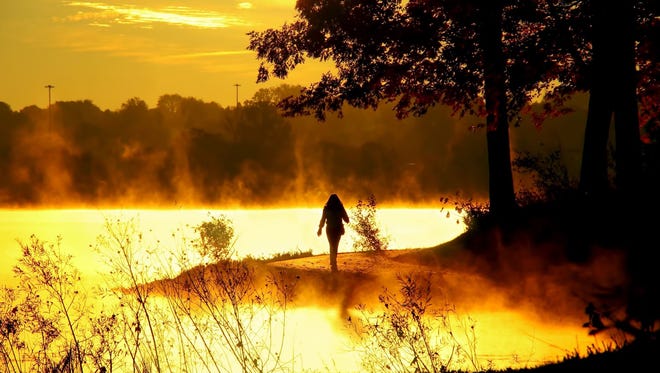 EDITOR'S CHOICE WINNER: "The Dawn Hiker" was shot at Kensington Metropark in Milford. "The sunrise and a persistent mist surrounded the hiker as she rounded the small peninsula in Kent Lake," said  Mudg Poster of West Bloomfield. "She walked so quickly I barely managed to get my camera up for this shot."