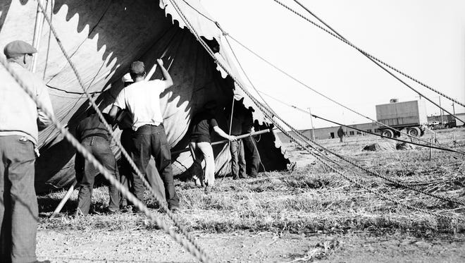 Circus workers get the poles under the canvas and prepare to raise the tent.