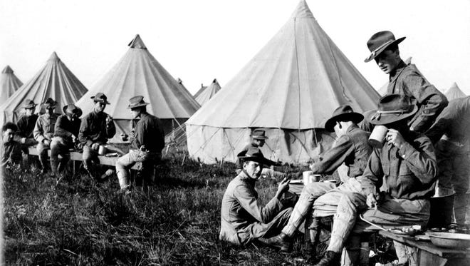 Soldiers sit around their tents and eat a meal at U.S. Army Camp Custer during World War I.