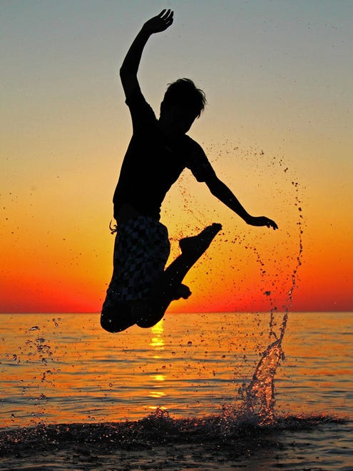 "Jumping into Summer," by Rachel Hamilton of Haslett.  A group of exchange students from Michigan and Japan were touring the coast of Lake Michigan. One day, "We were staying in Whitehall and decided to go to the beach to watch the sunset," she said. "My friend Rikuto wowed us all with his jumping form at Duck Lake State Park."