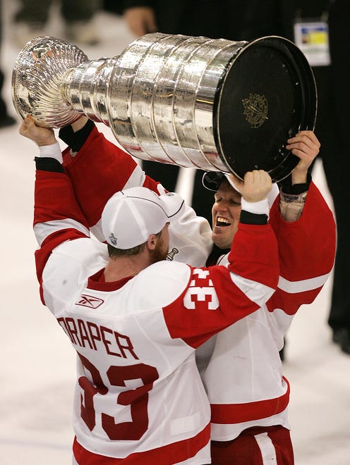 Detroit's Kris Draper hands the Stanley Cup to teammate Chris Osgood after the Red Wings defeated the Pittsburgh Penguins in the Stanley Cup Finals at Mellon Arena in Pittsburgh, Pennsylvania, on June 4, 2008.