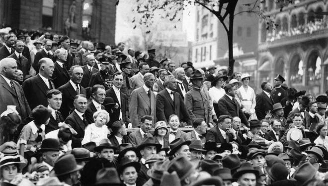Crowds stand and watch a conscription parade in Detroit during World War I. Henry Ford can be seen in the middle of the crowd.