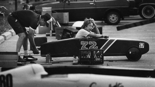 Jim Wheaton of Plymouth waits as his father, Bob, makes last-minute adjustments to his car during the Soap Box Derby at Ford Field in Dearborn in 1986.