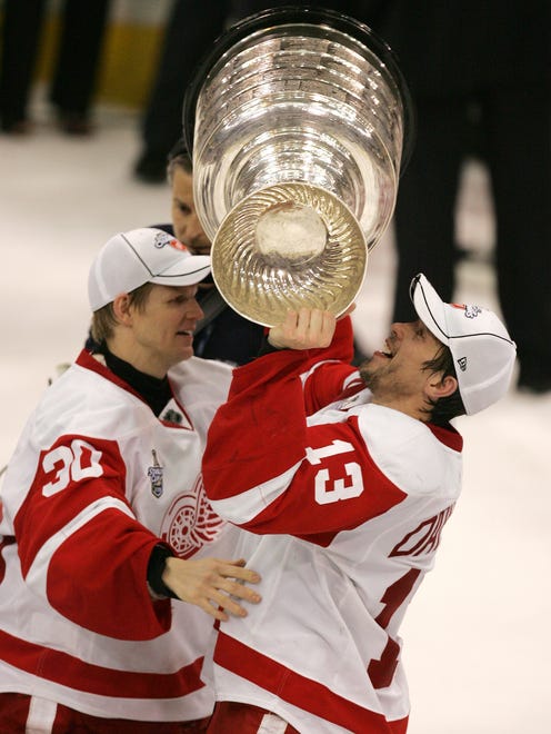 Detroit's Chris Osgood hands the Stanley Cup to teammate Pavel Datsyuk after the Red Wings defeated the Pittsburgh Penguins in the Stanley Cup Finals at Mellon Arena in Pittsburgh, Pennsylvania, on June 4, 2008.