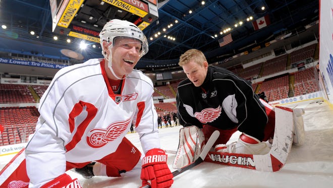 Kris Draper, left, and Chris Osgood, joke with each other while stretching before an alumni game with Chrysler Group executives and employees at Joe Louis Arena in Detroit, December 23, 2012.