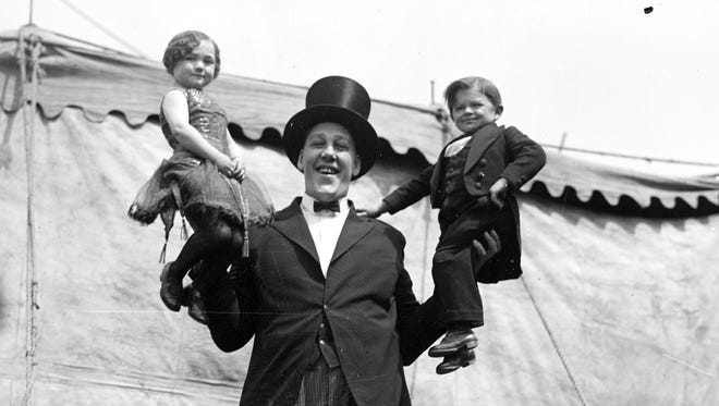 Johaan Aassen, a circus performer with the Al G. Barnes Amusement Co., holds a little person in each hand in 1923.