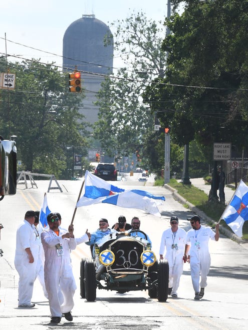 Team Wandering Troubadours of Finland with driver Jerome Reinan and navigator Chris Brugardt get escorted by Finland fans as they pull into Depot Town in their 1918 American LaFrance Speedster.