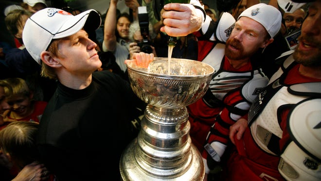 Kris Draper, right, pours more champagne into the Stanley Cup as goalie Chris Osgood waits his turn to drink from it after Detroit defeated the Pittsburgh Penguins in the Stanley Cup Finals at Mellon Arena in Pittsburgh, Pennsylvania, on June 4, 2008.