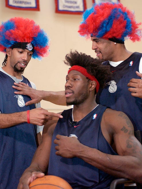 Detroit Pistons Richard Hamilton (from left) and Corliss Williamson help Ben Wallace as he prepares to get his hair done for "Wig Night" on March 12, 2004, at the Pistons' practice facility.