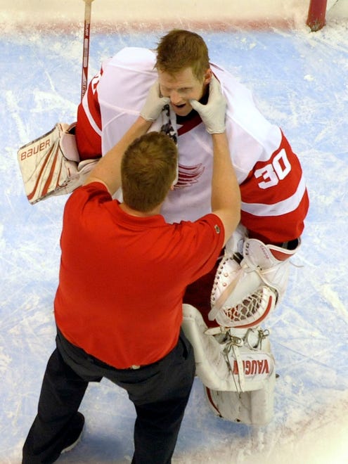 Athletic trainer Piet Van Zant checks out goalie Chris Osgood's jaw after Osgood took a puck to the mask during a game against the Nashville Predators at Joe Louis Arena,  October 30, 2010.