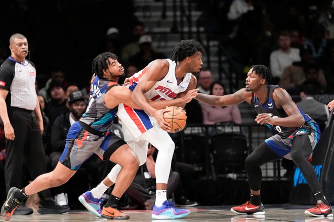 Brooklyn Nets guard Cam Thomas, front left, and forward Dorian Finney-Smith, right, guard against Detroit Pistons center James Wiseman, center, during the first half.