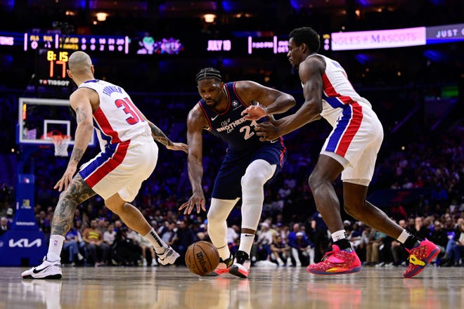Philadelphia 76ers' Joel Embiid, center, dribbles the ball between the defense of Detroit Pistons' Evan Fournier (31) and Jalen Duren (0) during the first half.
