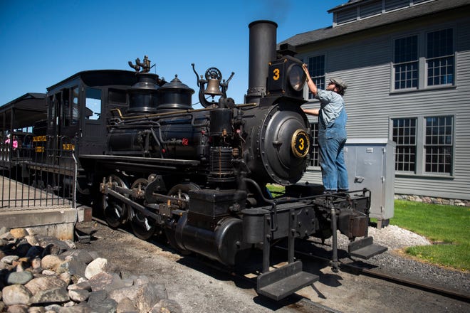 A staff member cleans the front of the Torch Lake steam locomotive during opening weekend at Greenfield Village on Saturday, April 13, 2024 in Dearborn.