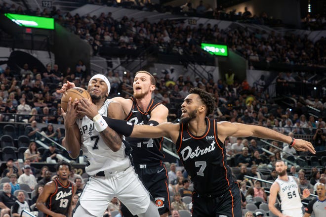 San Antonio Spurs guard David Duke, Jr., left, drives to the basket against Detroit Pistons guard Malachi Flynn, center, and guard Troy Brown, Jr., right, during the first half of an NBA basketball game, Sunday, April 14, 2024, in San Antonio. (AP Photo/Michael Thomas)