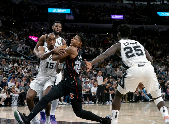 Detroit guard Marcus Sasser, center, drives to the basket against San Antonio Spurs guard Jamaree Bouyea, left, and forward Sidy Cissoko, right, during the second half of an NBA basketball game, Sunday, April 14, 2024, in San Antonio. (AP Photo/Michael Thomas)
