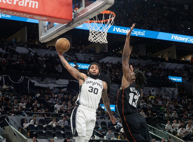 San Antonio Spurs forward Julian Champagnie (30) goes up for a dunk against Detroit Pistons center James Wiseman (13) during the first half of an NBA basketball game, Sunday, April 14, 2024, in San Antonio. (AP Photo/Michael Thomas)