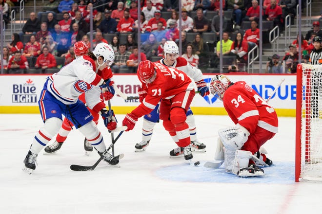Montreal left wing Juraj Slafkovsky, left, and right wing Cole Caufield try to get the puck past Detroit center Dylan Larkin and goaltender Alex Lyon during the second period.