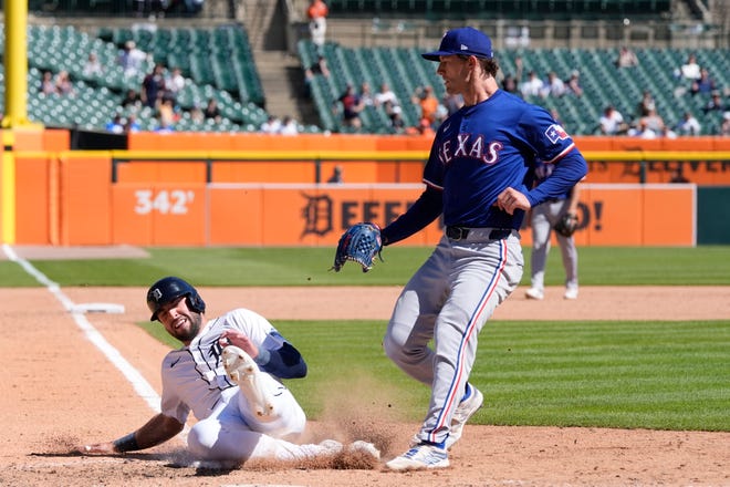 Detroit Tigers' Matt Vierling scores from third on a wild pass by Texas Rangers pitcher Jacob Latz, right, during the eighth inning.