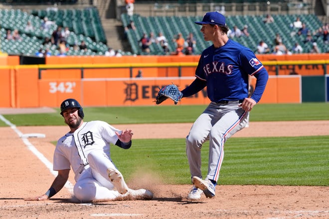 Detroit Tigers' Matt Vierling scores from third on a wild pass by Texas Rangers pitcher Jacob Latz, right, during the eighth inning.
