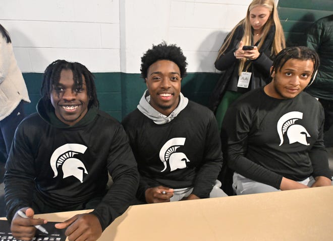 Michigan State cornerback Caleb Coley, quarterback Aidan Chiles and offensive lineman Brandon Baldwin sign autographs for fans before the Michigan State football's spring showcase/scrimmage at Spartan Stadium.
