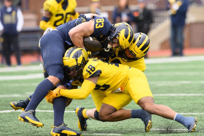 Team Blue tight end Zack Marshall is tackled by Team Maize linebacker John Weidenbach, top, and defensive back Ja'Den McBurrows in the fourth quarter of the annual spring game at Michigan Stadium.