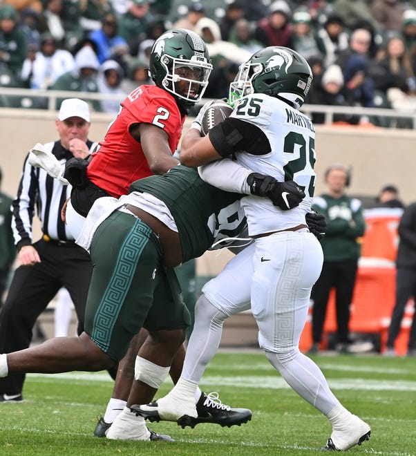 Defensive lineman D’Quan Douse breaks through the offensive line and brings down running back Joseph Martinez after the handoff from quarterback Aidan Chiles in the Michigan State football's spring showcase/scrimmage at Spartan Stadium.
