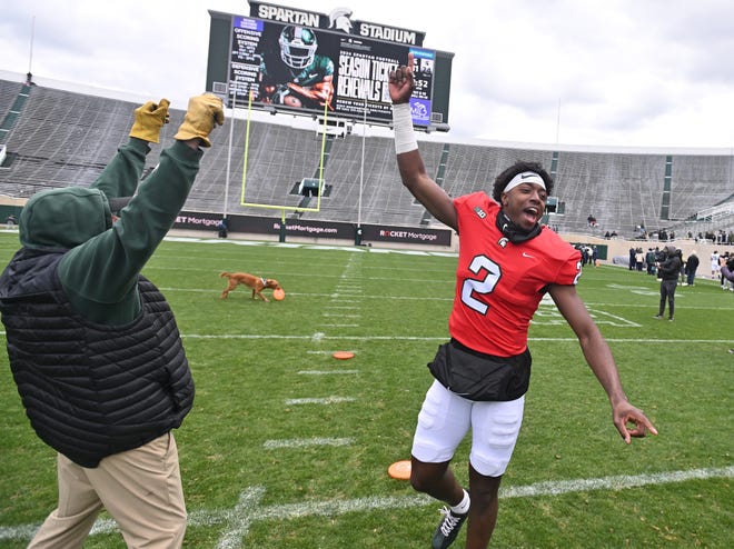 Quarterback Aidan Chiles celebrates after throwing the disc to Zeke the Wonder Dog, who eventually got one, possible due to throwing errors, after the Michigan State football's spring showcase/scrimmage at Spartan Stadium.