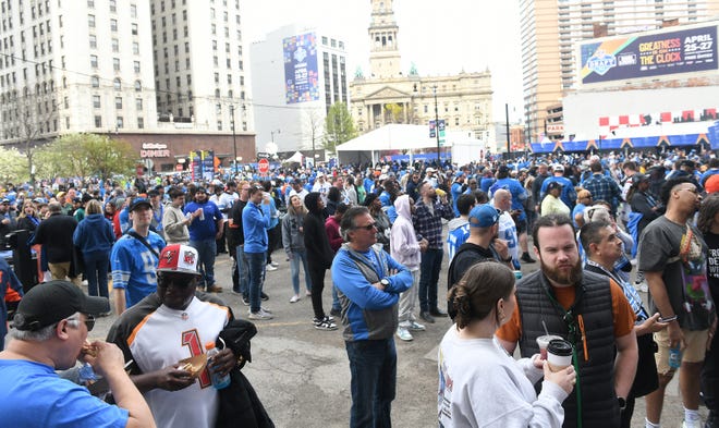 Fans eat and stand in line for food near Cadillac Square on Day 2 of the NFL Draft in Detroit.