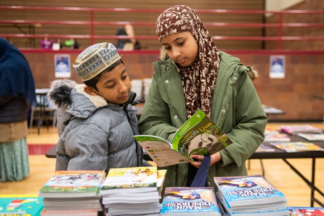 Hamtramck residents Nuhat Islam, 11, right, and Ehan Islam, 7, left, flip through a book together during a free book giveaway hosted by the Hamtramck Federation of Teachers and Reading Opens the World on Saturday, April 27, 2024 at the Hamtramck Community Center.