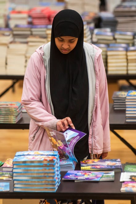 Tammy Islam of Hamtramck looks through a collection of thousands of books during a free book giveaway hosted by the Hamtramck Federation of Teachers and Reading Opens the World on Saturday, April 27, 2024 at the Hamtramck Community Center.