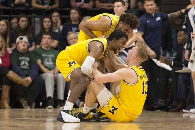 Zavier Simpson and Isaiah Livers of  Michigan celebrate with Ignas Brazdeikis after Brazdeikis made a basket and was fouled in the first half.