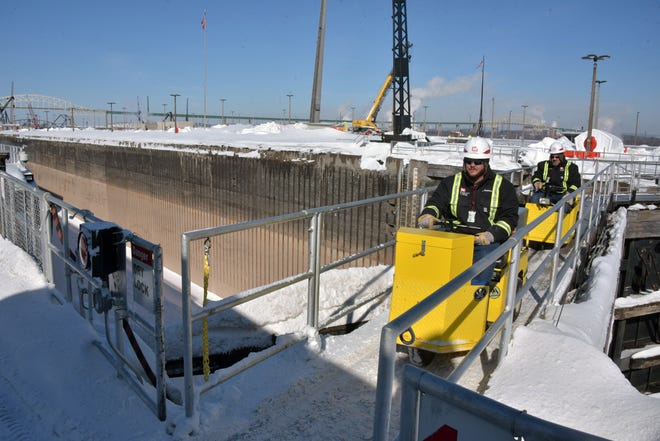 Two U.S. Corps of Engineers workmen drive scooters across a gate at the MacArthur Lock in Sault Ste. Marie. The electric scooters are used to move around the huge complex.