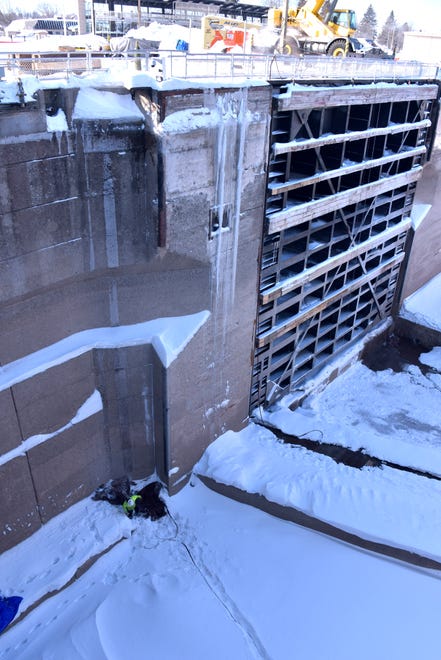 A U.S. Army Corps of Engineer, barely visible in his bright yellow safety coat, checks a drain at the bottom of the Poe Lock.