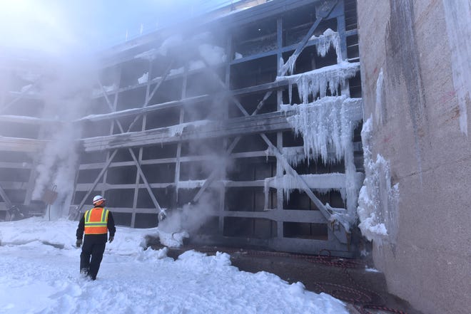 Steam rises against a water gate in the Poe Lock as U.S. Corps of Engineers' Jeff Harrington  inspects the ice cover. Steam is used to remove ice and snow from the dewatered lock, which has been without water for a 10-week winter maintenance and repair schedule.