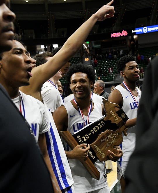 Lincoln guard Jalen Fisher (14), who hit the game-winner, holds the trophy.