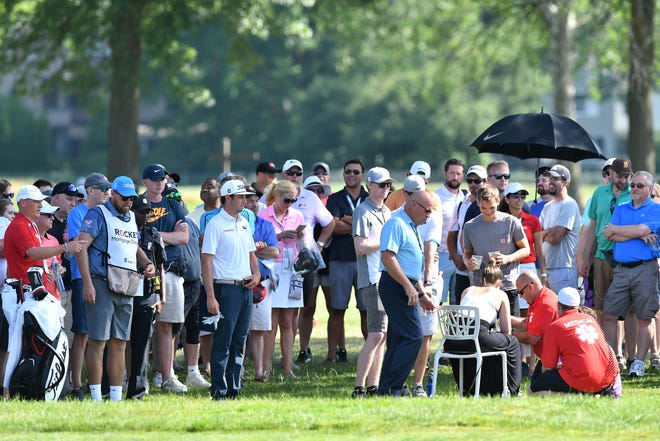 J.T. Poston, in white shirt and hat at left, waits while some medical attention is given to spectator who was hit by the ball that left the course on the 14th hole.