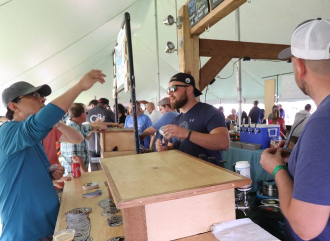 Jordan Frazier talks beer with a visitor to the Ore Dock Brewing stand at the Michigan Brewers Guild Summer Beer Festival in Riverside Park in Ypsilanti.