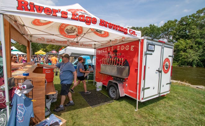Ryan Wiltse, co-owner of River's Edge Brewing, and his wife Carrie serve visitors from their trailer at the Huron River's edge in Ypsilanti's Riverside Park. Ryan Wiltse noted his actual brewpub is also located on the Huron River, but in Milford.