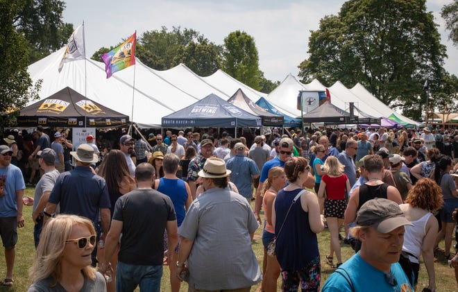 Attendees at the Michigan Brewers Guild's 2019 Summer Beer Festival crowd one of the event's main thoroughfares in Riverside Park in Ypsilanti Saturday.