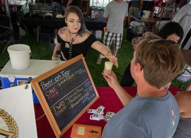 Catie Pietsch, representing Third Monk Brewing, of South Lyon, hands a beer sample to a visitor to the Michigan Brewers Guild 2019 Summer Beer Festival on Friday.