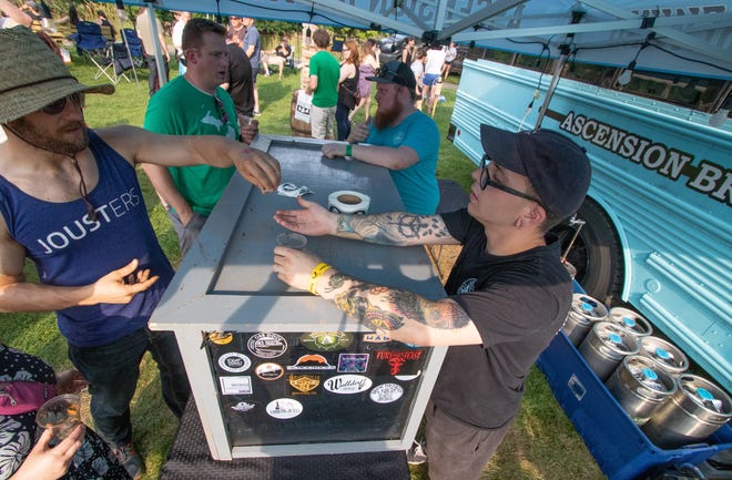 Ascension Brewing Company's David Murphy collects a beer token from a visitor to the Michigan Brewers Guild's 2019 Summer Beer Festival in Ypsilanti.